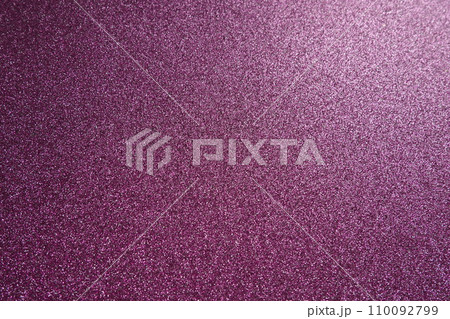 Light on a purple lilac pink violet surface. Bokeh glow. Festive shining background. New Year, Christmas, birthday. Plastic card design. Velvety rough paper, pink cardboard, slightly bent 110092799