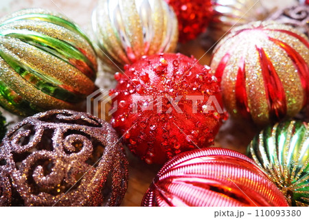 New Year's Christmas balls and decorations close up. A lot of decor of gold, red, yellow, brown, green, silver. Striped Christmas balls lie in a bunch. Festive beautiful colorful background. Design New Year's Christmas balls and decorations close up. A lot of decor of gold, red, yellow, brown, green, silver. Striped Christmas balls lie in a bunch. Festive beautiful colorful background. Design 110093380