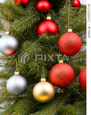 Beautiful red, gold, silver, yellow, beige shiny and matte Christmas balls shine on a spruce branch. Happy New Year. Merry Christmas. Christmas background - baubles and branch of spruce tree. 110093539