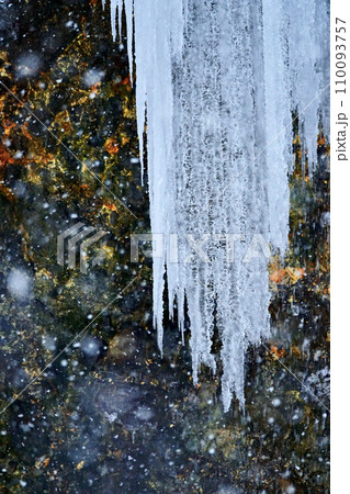 深々と降る雪の中にある氷柱 110093757