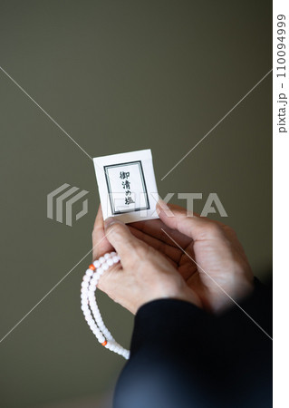 数珠を手にしてお浄めの塩を持っている葬式後の女性の手元 110094999