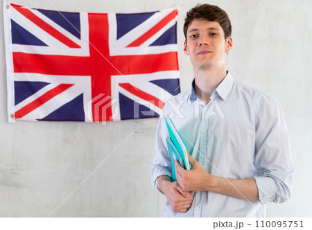 Male student with notebooks in his hands against background of the UK flag 110095751