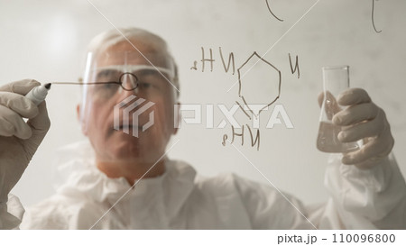 An elderly Caucasian male chemist in a protective suit writes on glass. An elderly Caucasian male chemist in a protective suit writes on glass. 110096800
