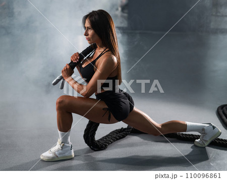 Caucasian woman holds the ropes and does a lunge in the exercise machine. Caucasian woman holds the ropes and does a lunge in the exercise machine. 110096861
