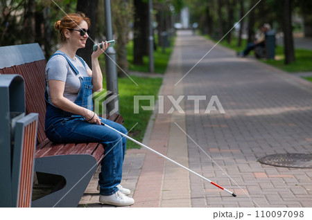 Happy blind pregnant woman sitting on bench and talking on smartphone.  110097098