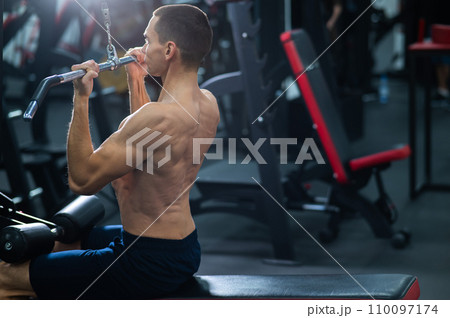 A man does a chest pulldown in the gym. A man does a chest pulldown in the gym. 110097174