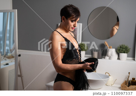Homosexual preening in front of the mirror. A transgender man combing a wig. Homosexual preening in front of the mirror. A transgender man combing a wig. 110097337
