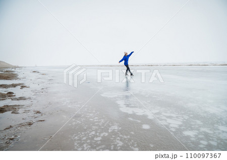 Caucasian woman in a blue sweater skating on a frozen lake. Caucasian woman in a blue sweater skating on a frozen lake. 110097367