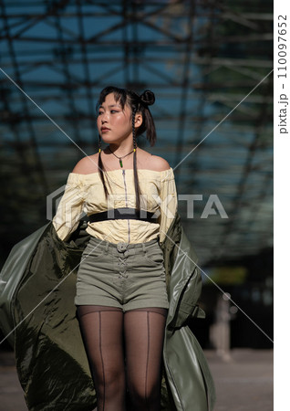 A beautiful Asian woman in shorts and a green leather coat comes out of the subway. A beautiful Asian woman in shorts and a green leather coat comes out of the subway. 110097652