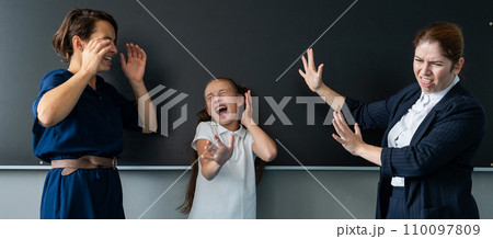 The female teacher screams at the schoolgirl and her mother standing at the blackboard. The female teacher screams at the schoolgirl and her mother standing at the blackboard. 110097809