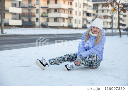 An injured young girl waits for help while sitting in the snow. An injured young girl waits for help while sitting in the snow. 110097820