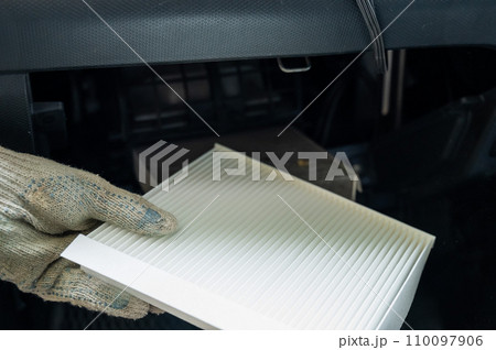 A mechanic changes the cabin air filter of a car. A mechanic changes the cabin air filter of a car. 110097906