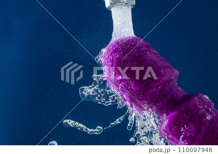 Purple vibrator under running water on a blue background. waterproof sex toy. Purple vibrator under running water on a blue background. waterproof sex toy. 110097946