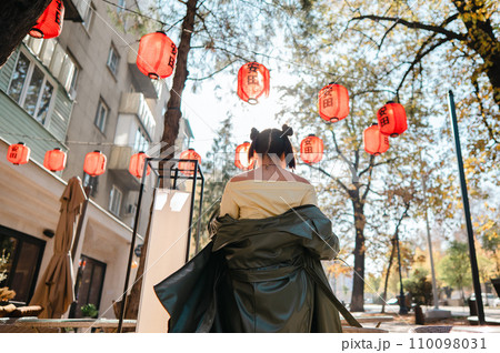 Portrait of an Asian woman against the background of Chinese lanterns outdoors. Portrait of an Asian woman against the background of Chinese lanterns outdoors. 110098031