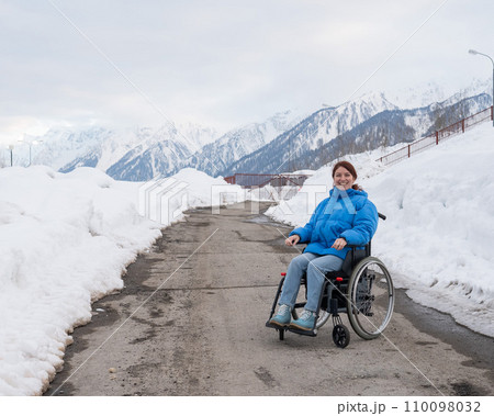 Caucasian woman in a wheelchair travels in the mountains in winter. Caucasian woman in a wheelchair travels in the mountains in winter. 110098032