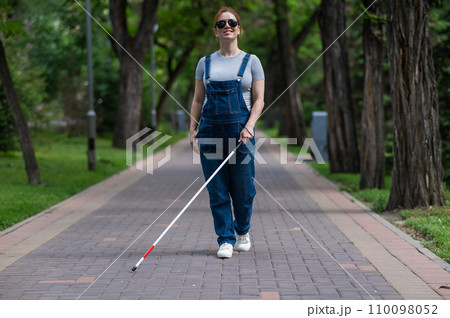 Blind pregnant woman walking in the park with a cane. Blind pregnant woman walking in the park with a cane. 110098052