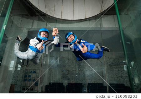 A man and a woman enjoy a joint flight in a wind tunnel and give a thumbs up. Free fall simulator. A man and a woman enjoy a joint flight in a wind tunnel and give a thumbs up. Free fall simulator. 110098203
