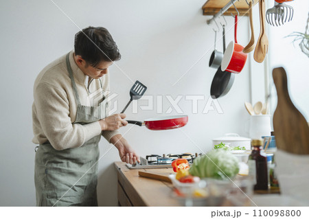 キッチンで料理をする30代半ばの男性 110098800