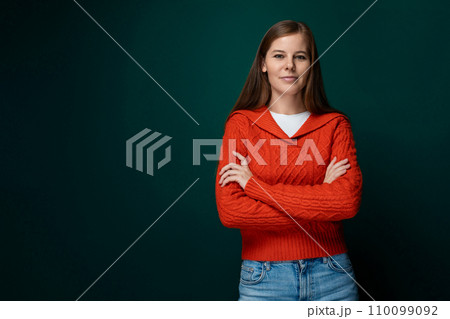 Well-groomed 30 year old woman with brown hair wears a red knitted sweater on a green background Well-groomed 30 year old woman with brown hair wears a red knitted sweater on a green background 110099092