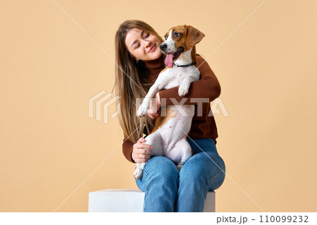 Portrait of cute Beagle on hands of attractive happy smiling young woman. Love and friendship between dog and human. Portrait of cute Beagle on hands of attractive happy smiling young woman. Love and friendship between dog and human. 110099232