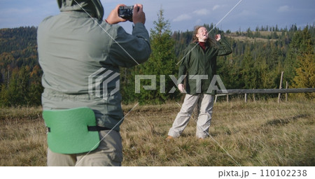Caucasian man takes photos of woman during hike in mountains 110102238