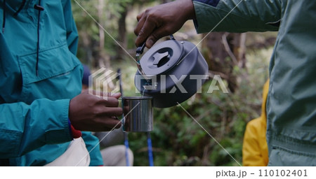 Tourist keeps metal cup in hand, other traveler pours hot water 110102401
