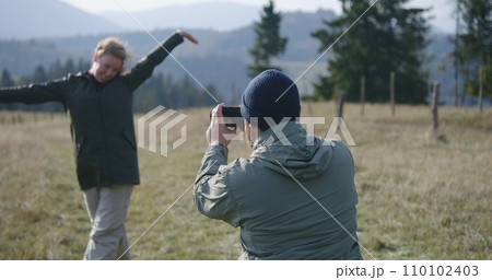 Man takes pictures of his wife during hiking trip using camera Man takes pictures of his wife during hiking trip using camera 110102403