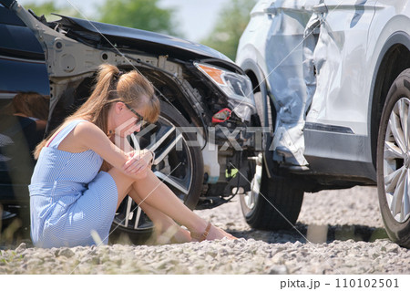 Stressed woman driver sitting on street side shocked after car accident. Road safety and insurance concept Stressed woman driver sitting on street side shocked after car accident. Road safety and insurance concept 110102501