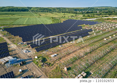 Aerial view of big electric power plant under construction with many rows of solar panels on metal frame for producing clean electrical energy. Development of renewable electricity sources Aerial view of big electric power plant under construction with many rows of solar panels on metal frame for producing clean electrical energy. Development of renewable electricity sources 110102653