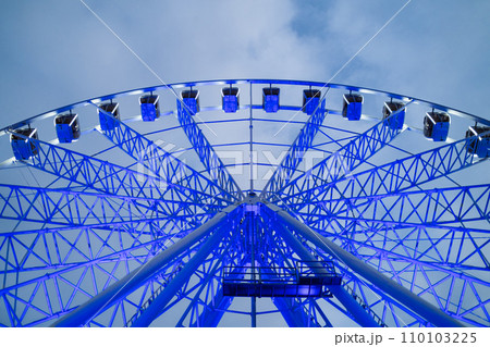 Underside view of colorful ferris wheel over evening sky at amusement park. 110103225