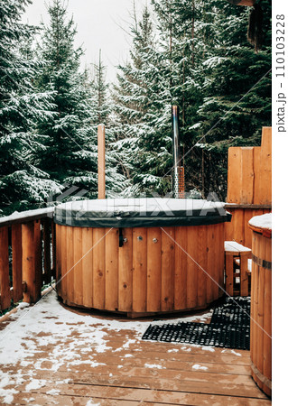 Open-air bath interior near forest, winter, snow view. Wooden hot tub outside Open-air bath interior near forest, winter, snow view. Wooden hot tub outside 110103228