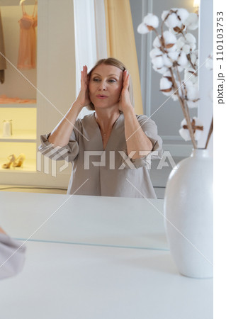 Senior woman sitting in front of mirror at home 110103753