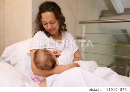 Beautiful loving Latin American mother breastfeeding her baby. Maternity leave and infancy concept. Copy advertising space Beautiful loving Latin American mother breastfeeding her baby. Maternity leave and infancy concept. Copy advertising space 110104876