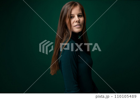 Portrait of a well-groomed young woman with brown eyes on a dark green background 110105489
