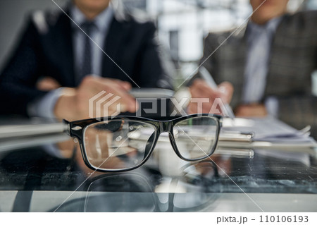 glasses on the table in the office on a blurred background of colleagues 110106193