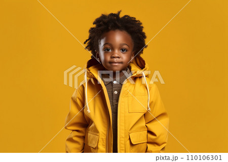 African American child, portrait of boy in jacket stands isolated on yellow background. Little black kid in casual clothes poses against studio wall. Concept of young and school African American child, portrait of boy in jacket stands isolated on yellow background. Little black kid in casual clothes poses against studio wall. Concept of young and school 110106301