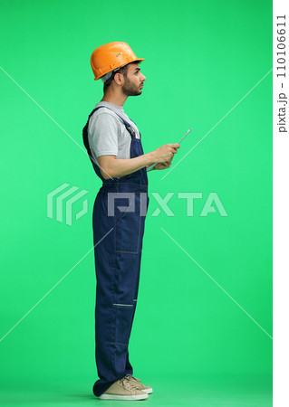 A builder male on a green background thinking. In profile 110106611