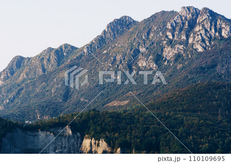Beautiful landscape of the layered misty hazy Italian Alps mountain range during evening. Lombardy, Italy 110109695