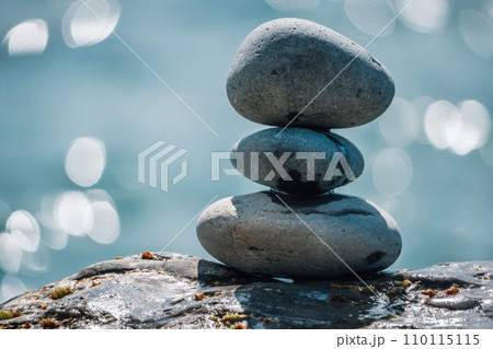Pyramid stones on the seashore on a sunny day on the blue sea background. Happy holidays. Pebble beach, calm sea, travel destination. Concept of happy vacation on the sea, meditation, spa, calmness. Pyramid stones on the seashore on a sunny day on the blue sea background. Happy holidays. Pebble beach, calm sea, travel destination. Concept of happy vacation on the sea, meditation, spa, calmness. 110115115