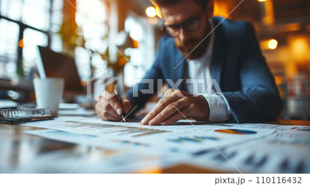 A businessman processes information in printed documents, analyzes financial information based on the results of trading on the securities market, blurred background, low angle shooting 110116432
