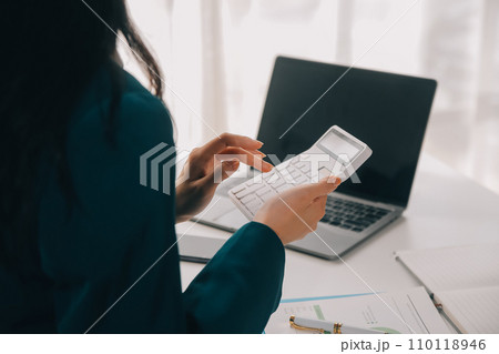 Businessman using a calculator to calculate numbers on a company's financial documents, he is analyzing historical financial data to plan how to grow the company. Financial concept. 110118946