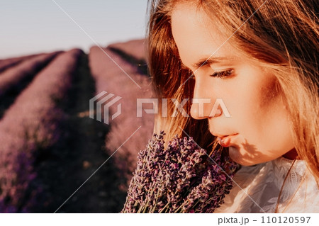 Woman lavender field. Happy carefree woman in a white dress walking in a lavender field and smelling a lavender bouquet on sunset. Ideal for warm and inspirational concepts in wanderlust and travel. Woman lavender field. Happy carefree woman in a white dress walking in a lavender field and smelling a lavender bouquet on sunset. Ideal for warm and inspirational concepts in wanderlust and travel. 110120597