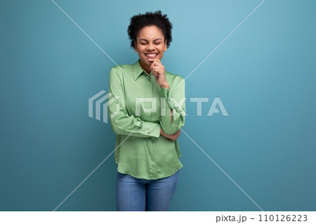 young brunette hispanic woman with curly hair dressed in a green blouse on a background with copy 110126223