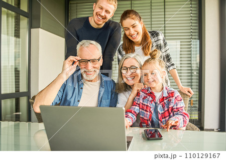 Happy family watching together video online in a laptop while sitting at home 110129167