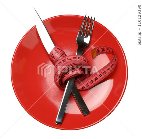 Red round plate and fork and knife wrapped in green measuring tape Red round plate and fork and knife wrapped in green measuring tape 110129390
