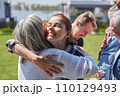 Happy woman embracing her mother while standing at the green grass lawn 110129493