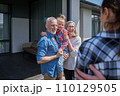 Senior couple holding little girl at the hands and feeling happy at the summer 110129505