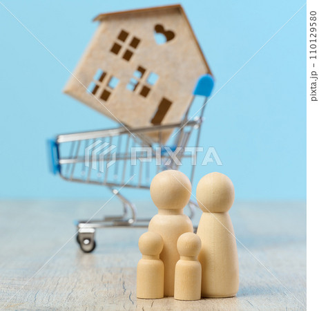Wooden house and miniature figurines of a family on a blue background. The concept of selling and buying real estate 110129580