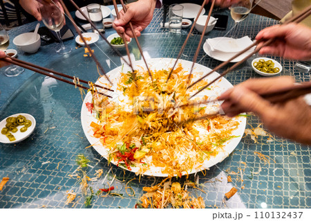 People mixing and tossing yusheng or yee sang during Chinese New Year dinner celebration. Slow shutter speed with motion blur intended. People mixing and tossing yusheng or yee sang during Chinese New Year dinner celebration. Slow shutter speed with motion blur intended. 110132437