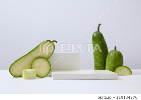 Over white background, geometric shaped podiums displayed with winter melon slices. Research indicates that Winter melon (Benincasa hispida) is rich in polyphenols 110134276